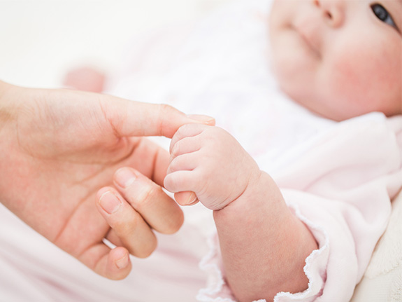 写真：母親の指を握る赤ちゃん